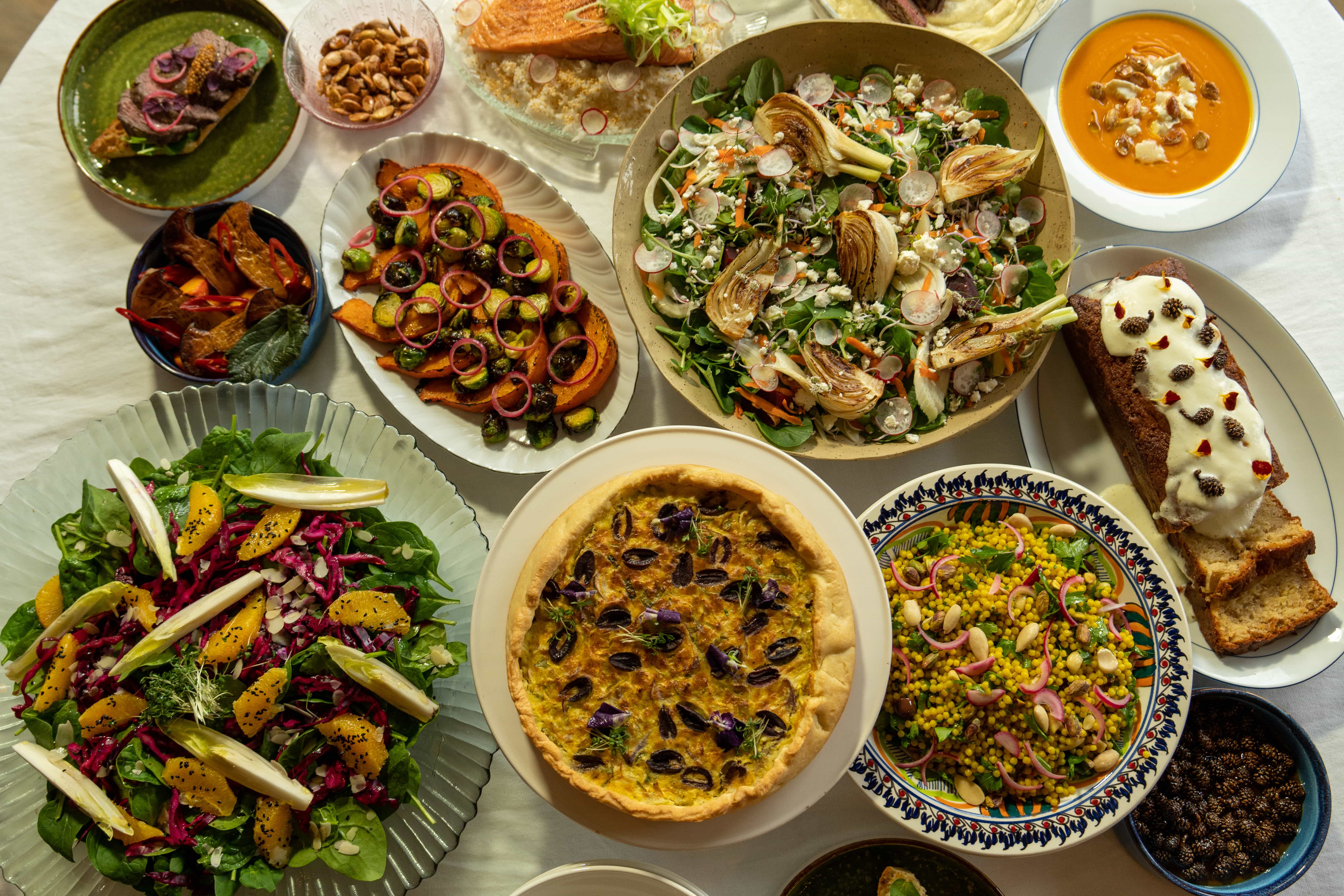 Buffettafel met quiche, salades en couscoussalade op kleurrijk servies
